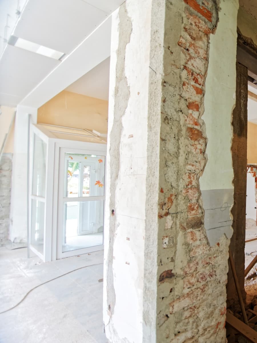 Interior under construction showing an exposed brick pillar with stripped plaster